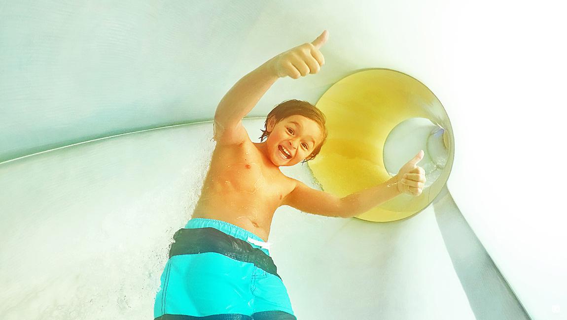 Boy giving a thumbs up as he rides down the slide