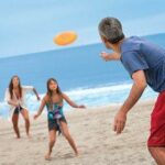 family playing frisbee on the beach