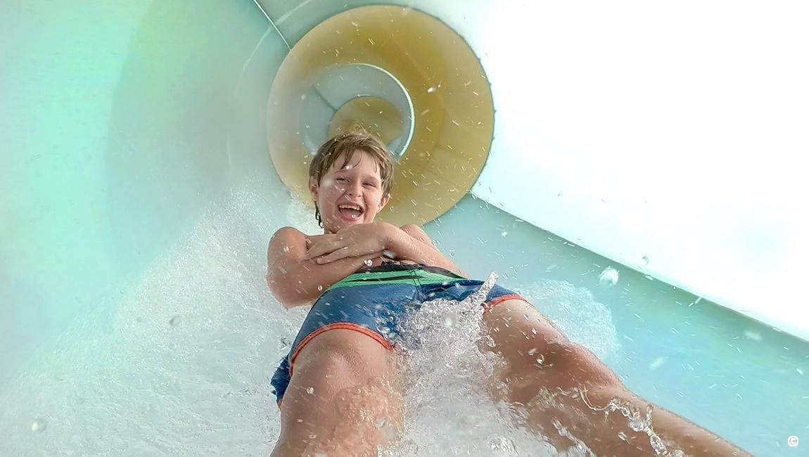 Boy sliding down a Crown Reef waterpark slide